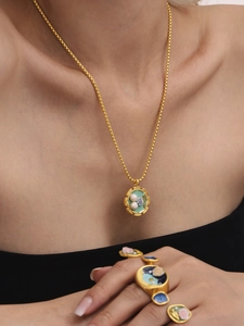 Dettaglio di collana e anelli vintage dorati con smalto verde e perle d'acqua dolce
