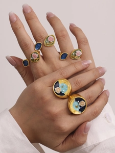 Dettaglio di anelli vintage in smalto con perle indossati su una mano elegante