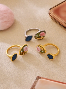 Dettaglio di anelli con rose vintage, smalto verde e piccole perle in finitura oro