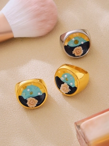 Dettagli di anelli spessi in oro e argento con rosa in smalto e motivi a rilievo