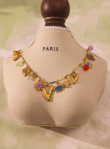 Detail of 18k gold plated necklace with colorful enamel charms on jewelry display