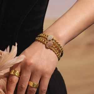 Gold cuban chain bracelet with pavé zircon centerpiece and textured wide band rings