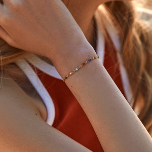 Detailaufnahme des goldenen Gliederkettenarmbands mit bunten Perlen am Handgelenk