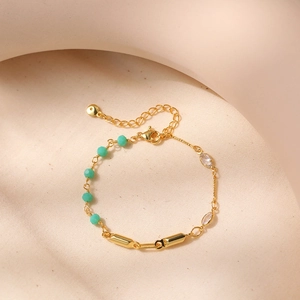 Detalle de pulsera de turquesa con barras bañadas en oro de 18k y dijes de circonita