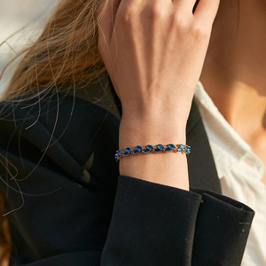 Leaf-inspired gold bracelet with marquise-cut navy blue gemstones on model wrist