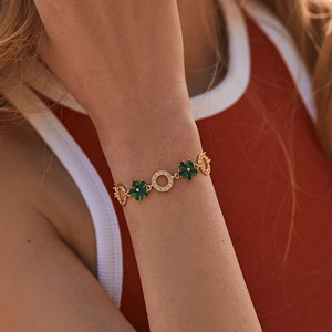 Elegant gold bracelet featuring green floral gemstones and crystal encrusted round links