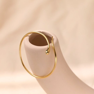 Macro-opname van gepolijste 18K vergulde minimalistische slang open armband op display