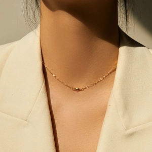 Collar gargantilla minimalista chapado en oro con colgante de grano usado sobre blazer