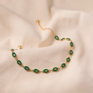 Detailansicht eines Vintage Gold-Fußkettchens mit grünen Emaille-Anhängern
