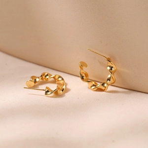 Detailed macro view of twisted gold hoop earrings with polished spiral design and metallic shine