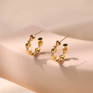 Macro detail of gold-plated twisted spiral C-hoop earrings with a mirror-polished finish