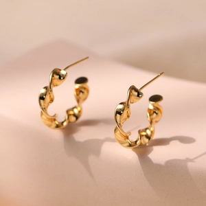 Polished golden geometric twisted hoop earrings with a sleek minimalist ripple design