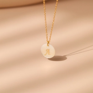 Détail macro d'un collier en laiton plaqué or 18K avec pendentif en nacre et lettre A