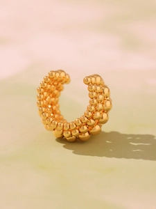 Macro shot of gold multi-layer beaded ear cuff with detailed grain texture and C-shape