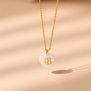 Détail du collier plaqué or avec pendentif rond en nacre et lettre B finement gravée