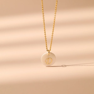 Détail d'un collier en laiton plaqué or 18 carats avec pendentif en nacre et lettre D