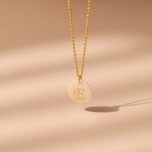 Détail du collier en laiton plaqué or 18K avec incrustation en nacre et lettre E