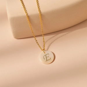 Détail du collier en laiton plaqué or 18 carats avec lettre E sur pendentif en nacre