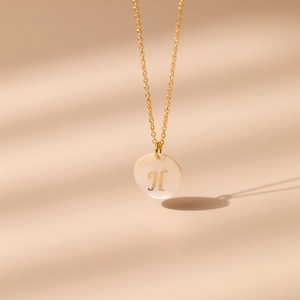 Détail du collier plaqué or 18 carats avec nacre ronde et pendentif lettre H dorée