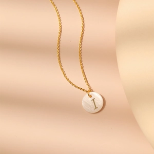 Détail macro du pendentif en nacre avec initiale I et chaîne en plaqué or 18 carats