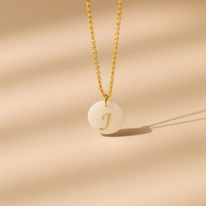 Vue macro d'un collier en laiton plaqué or 18 carats avec pendentif en nacre et lettre J