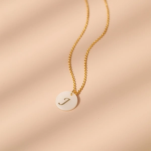Vue macro détaillée du collier en laiton doré 18 carats avec pendentif lettre J en nacre