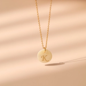 Détail macro du collier en laiton plaqué or 18K avec pendentif en nacre et la lettre K