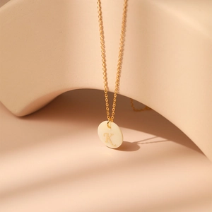 Détail d'un collier lettre K en or 18 carats avec base en nacre naturelle et chaîne fine