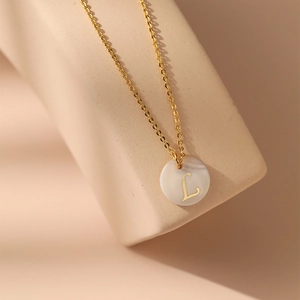 Détail macro du collier plaqué or 18 carats avec pendentif en nacre et lettre L