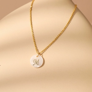 Gros plan détaillé du pendentif lettre M en or 18 carats avec nacre naturelle élégante