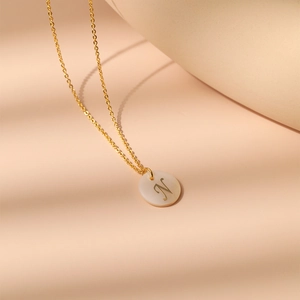 Gros plan d'un collier en laiton plaqué or 18K avec pendentif nacre et la lettre N