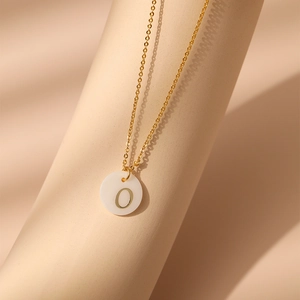 Détail du collier en laiton plaqué or 18K avec pendentif nacre blanche et gravure lettre O
