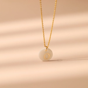 Gros plan du pendentif lettre O sur collier en laiton plaqué or 18K avec incrustation nacre