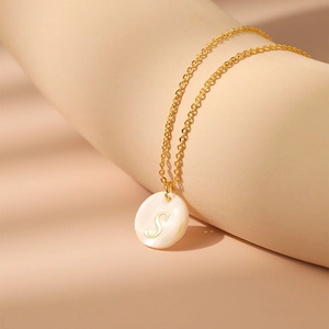 Détail macro du collier plaqué or 18 carats avec pendentif en nacre et la lettre S