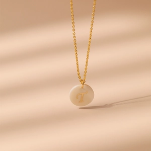 Détail macro d'un collier plaqué or 18 carats avec pendentif en nacre et la lettre T