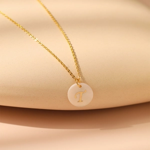 Détail du collier en laiton plaqué or 18K avec lettre T sur pendentif rond en nacre