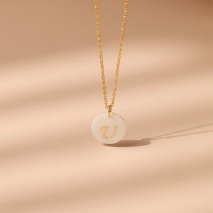 Gros plan détaillé du collier en laiton plaqué or 18K avec pendentif en nacre et lettre V