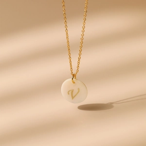 Détail du collier en laiton plaqué or 18 carats avec lettre V sur pendentif en nacre