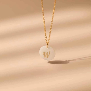 Détail du collier en laiton plaqué or 18K montrant le pendentif rond en nacre avec lettre W