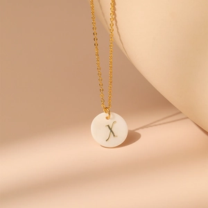 Vue détaillée d'un collier en laiton plaqué or 18 carats avec pendentif en nacre et lettre X gravée