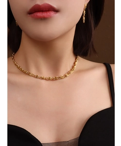 Nahaufnahme eines goldenen gedrehten Chokers und passender Ohrringe am Modell