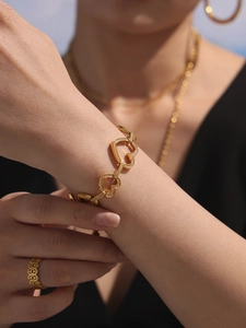 Détail d'un bracelet gourmette doré en forme de cœur avec zircons sur un poignet