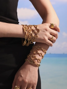 Détail de bracelets en chaîne dorée avec cœurs et zircons 5A sur un fond de plage