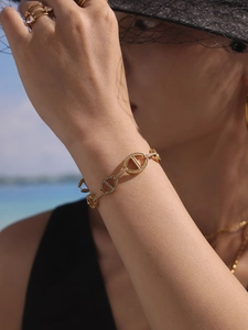 Détail du bracelet chaîne en or 18K avec cœur en zircons et bague assortie à la plage