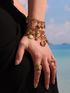 Gros plan de bracelets et bagues dorés style océan avec coquillages et dauphins