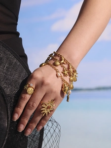 Primer plano de pulsera multicapa de oro con dijes de conchas y detalles de estrellas de mar