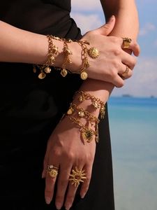 Vue détaillée de bracelets dorés avec breloques soleil et coquillages sur un mannequin