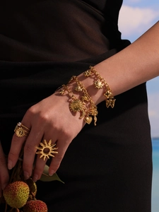 Détail d'un bracelet doré avec pendentifs soleil et cœur au style vintage bohème