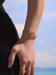 Détail du bracelet en or avec cercles évidés et zircons scintillants sous le soleil d'été