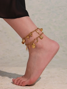 Détail de bracelets de cheville dorés avec breloques étoile de mer et lune sur modèle